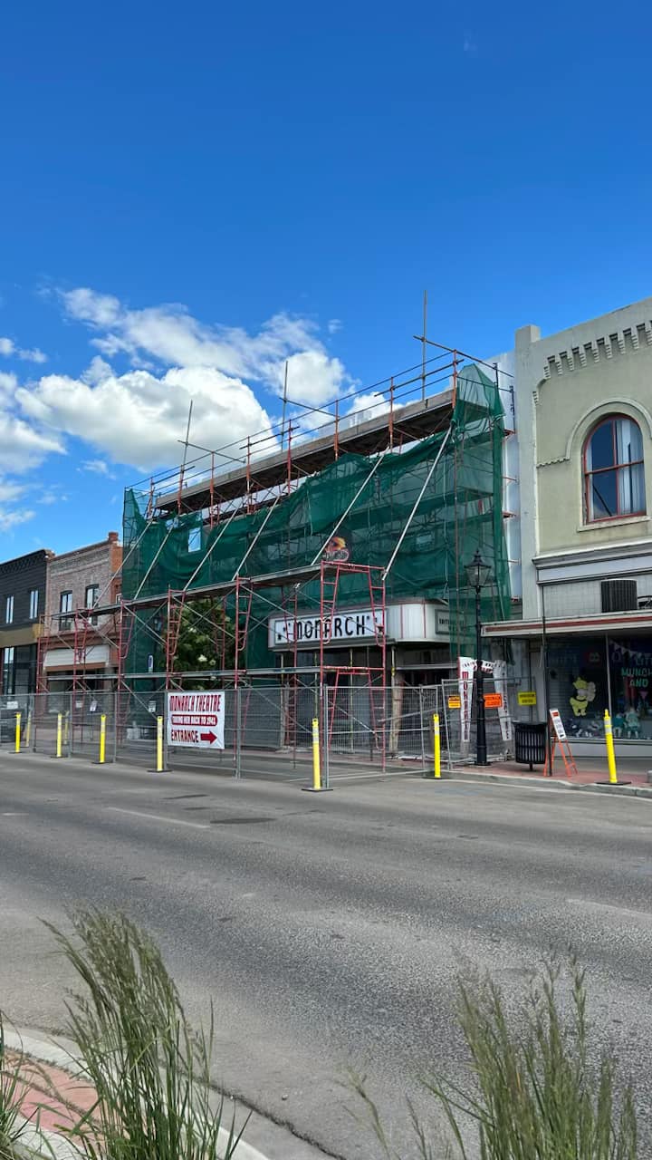 A quiet, empty street in a small town with a mix of older buildings and shops on both sides.